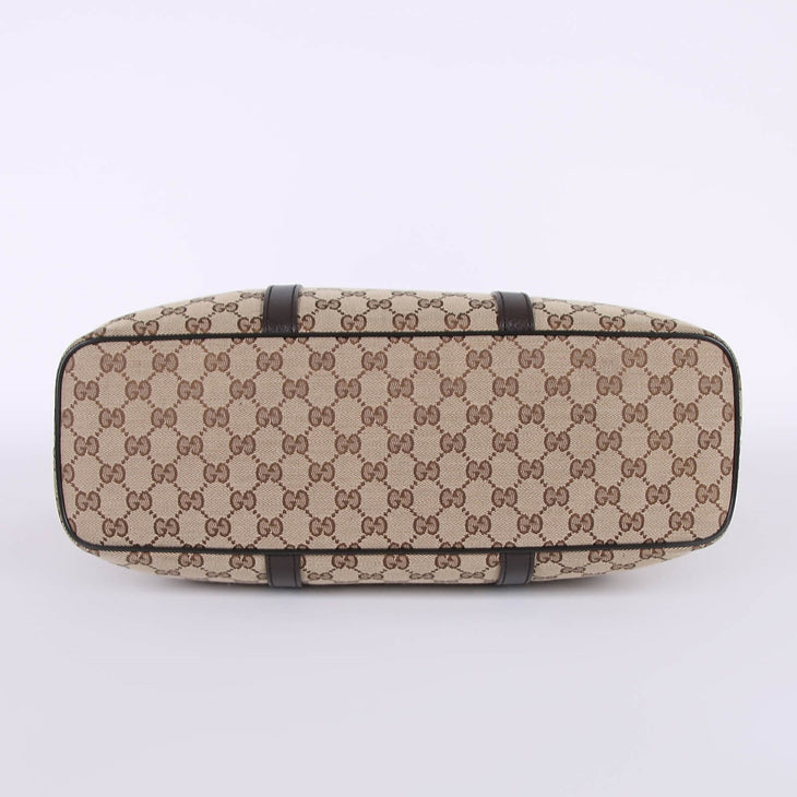 Bottom view of beige GG monogram canvas tote bag with brown leather trim and protective feet — Gucci | Endless UAE