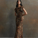 Woman wearing tiger stripe maxi dress with short puffed sleeves against textured background — De La Vali | Endless UAE