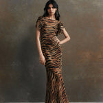 Woman wearing tiger stripe maxi dress with short puffed sleeves against textured background — De La Vali | Endless UAE