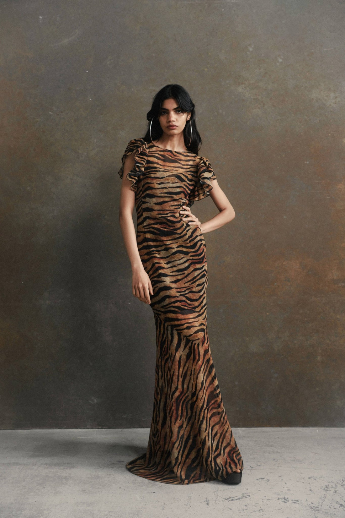 Woman wearing tiger stripe maxi dress with short puffed sleeves against textured background — De La Vali | Endless UAE