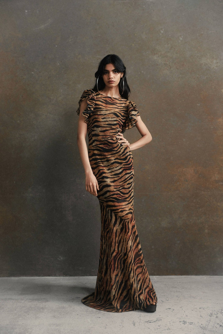 Woman wearing tiger stripe maxi dress with short puffed sleeves against textured background — De La Vali | Endless UAE