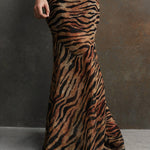 Woman wearing tiger stripe maxi dress with short puffed sleeves against textured background — De La Vali | Endless UAE