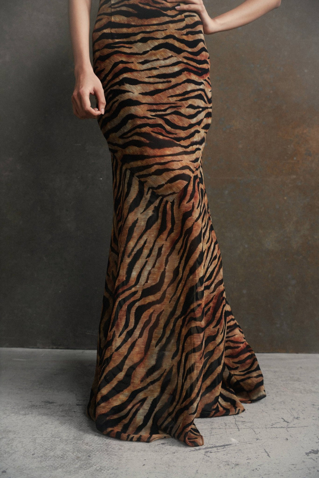 Woman wearing tiger stripe maxi dress with short puffed sleeves against textured background — De La Vali | Endless UAE