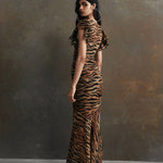 Woman wearing tiger stripe maxi dress with short puffed sleeves against textured background — De La Vali | Endless UAE