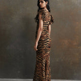 Woman wearing tiger stripe maxi dress with short puffed sleeves against textured background — De La Vali | Endless UAE