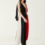 Woman wearing pleated asymmetric maxi dress in black, blush pink and red with black ankle strap heels — Victoria Beckham | Endless UAE