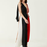 Woman wearing pleated asymmetric maxi dress in black, blush pink and red with black ankle strap heels — Victoria Beckham | Endless UAE