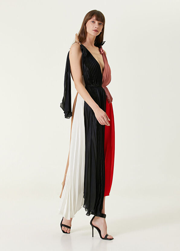 Woman wearing pleated asymmetric maxi dress in black, blush pink and red with black ankle strap heels — Victoria Beckham | Endless UAE
