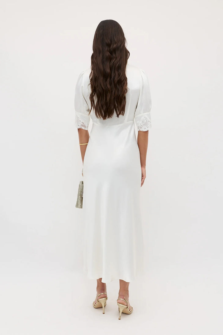 White midi dress with lace sleeve details and gold clutch, rear view — Rixo | Endless UAE