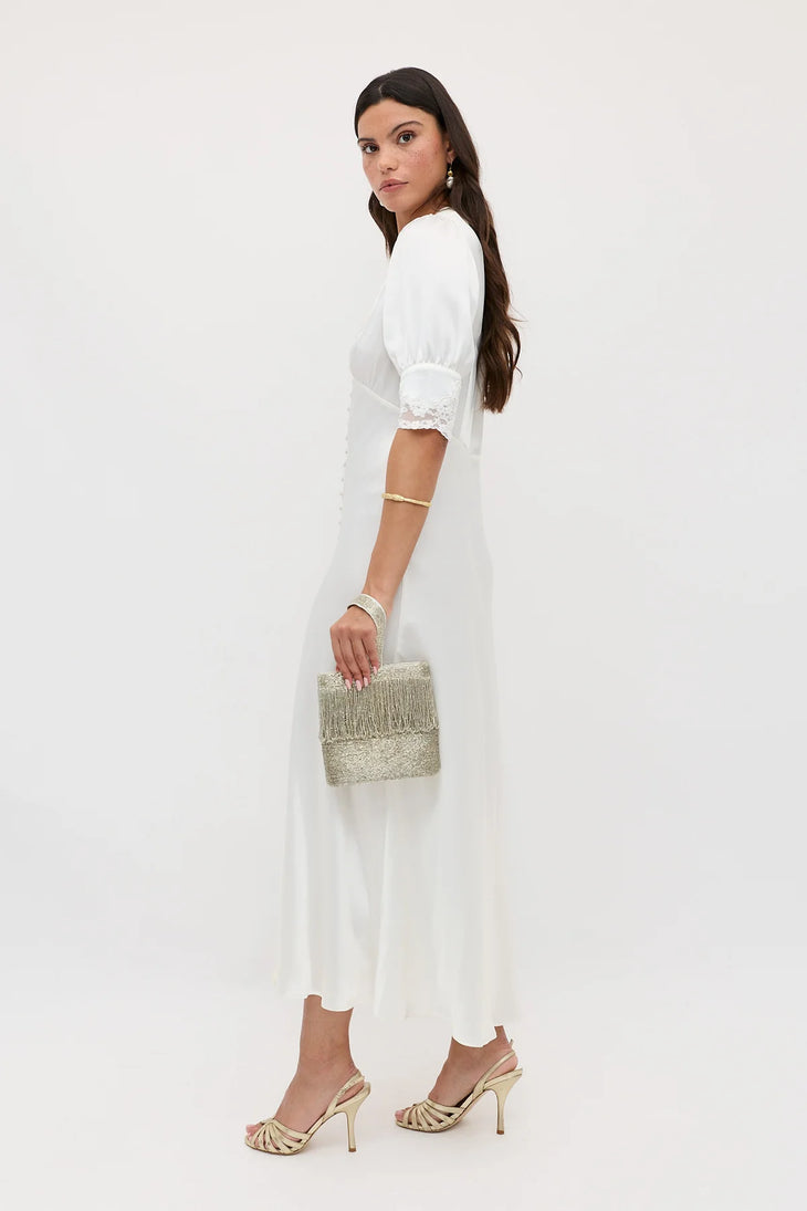 Elegant white midi dress with puffed lace-trimmed sleeves and flowing skirt, styled with gold accessories and heels — Rixo | Endless UAE