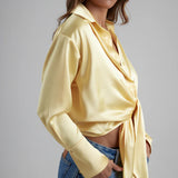 Woman wearing yellow tie-up shirt with blue jeans against gray background — By Keara | Endless UAE