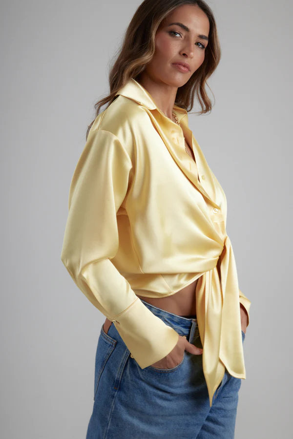 Woman wearing yellow tie-up shirt with blue jeans against gray background — By Keara | Endless UAE