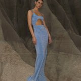 Blue sequined maxi dress with asymmetric cutout detail and thin straps on model against rock formation — Baobab | Endless UAE