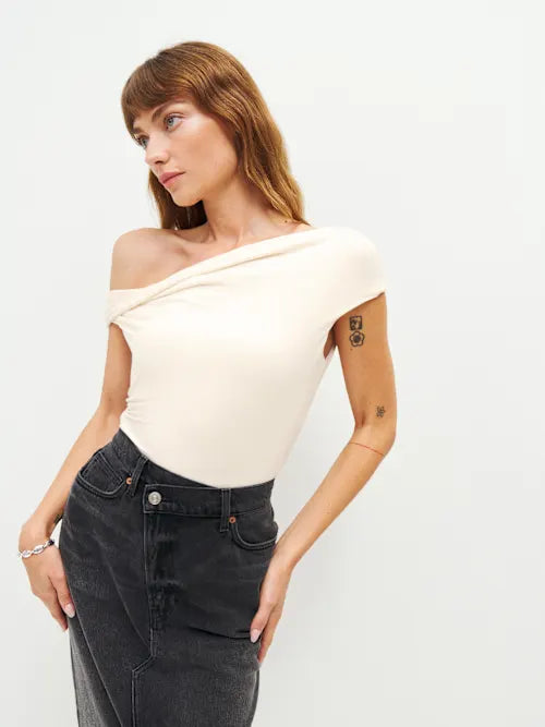 Woman wearing cream off-shoulder Cello Knit Top with black denim skirt and nude heels — Reformation | Endless UAE