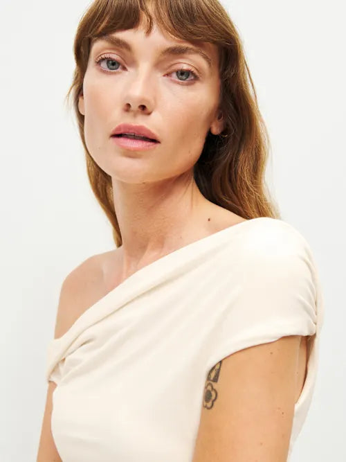 Woman wearing cream off-shoulder Cello Knit Top with black denim skirt and nude heels — Reformation | Endless UAE