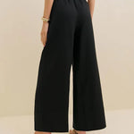 Black linen wide leg pants with elastic waistband shown from back view on model with crop top and sandals — Reformation | Endless UAE
