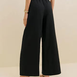 Black linen wide leg pants with elastic waistband shown from back view on model with crop top and sandals — Reformation | Endless UAE