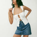 White linen crop top with tie-front cutout detail and wide straps paired with denim mini skirt — Reformation | Endless UAE