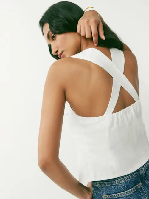 White linen halter top with crossed back straps and open back detail, styled with denim jeans — Reformation | Endless UAE
