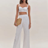 White lace-trimmed crop top and wide-leg pants two piece set with straw clutch and strappy heels — Reformation | Endless UAE