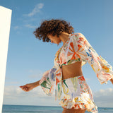 Woman wearing colorful printed crop top and shorts beach co-ord set with bell sleeves by the ocean — Charo Ruiz Ibiza | Endless UAE