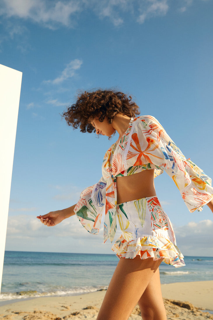 Woman wearing colorful printed crop top and shorts beach co-ord set with bell sleeves by the ocean — Charo Ruiz Ibiza | Endless UAE