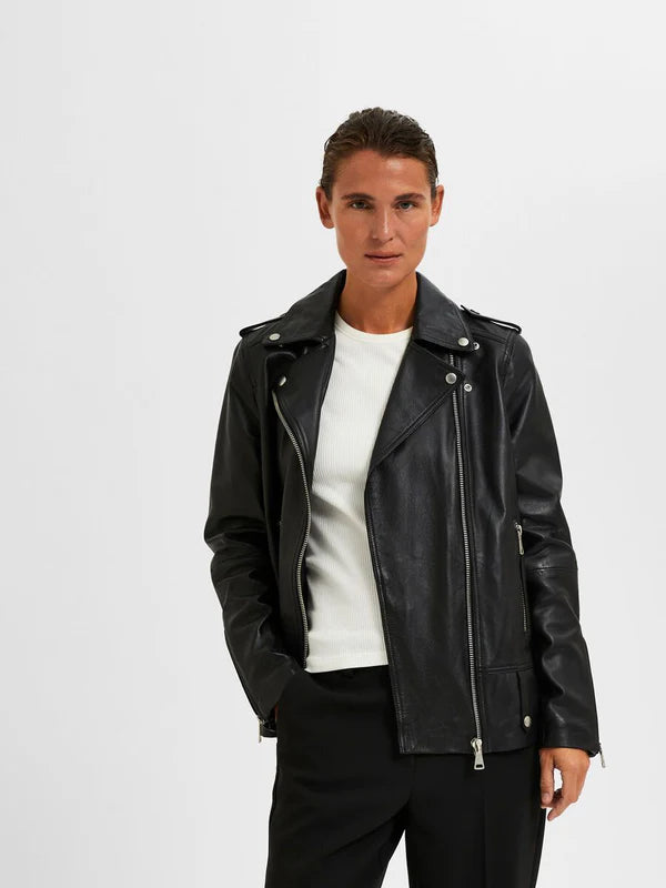 Woman wearing black leather biker jacket with silver zippers over white knit top and black pants — Selected Femme | Endless UAE