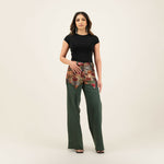 Woman wearing black top with patchwork embellished belt detail and green wide-leg denim pants — Quab | Endless UAE