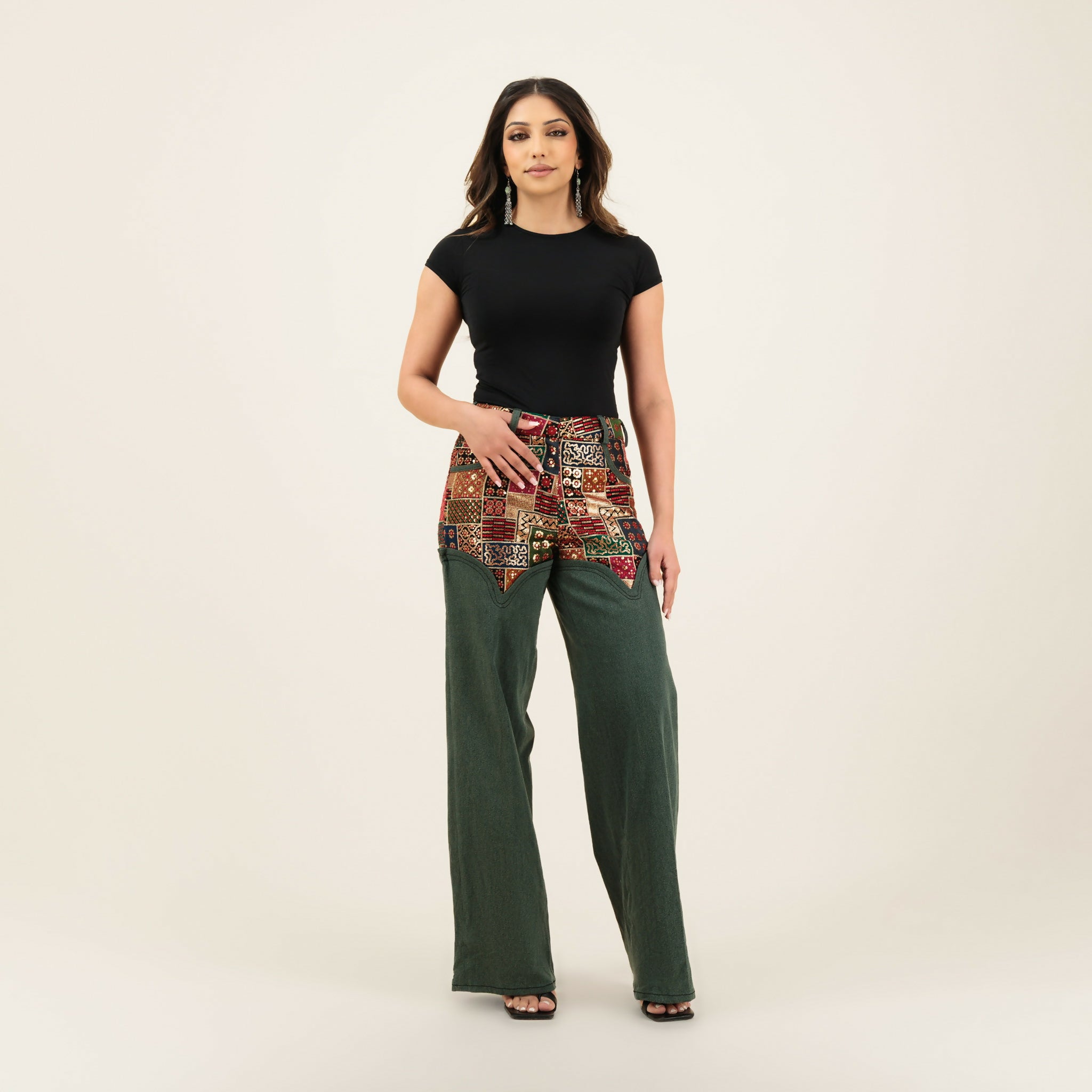 Woman wearing black top with patchwork embellished belt detail and green wide-leg denim pants — Quab | Endless UAE