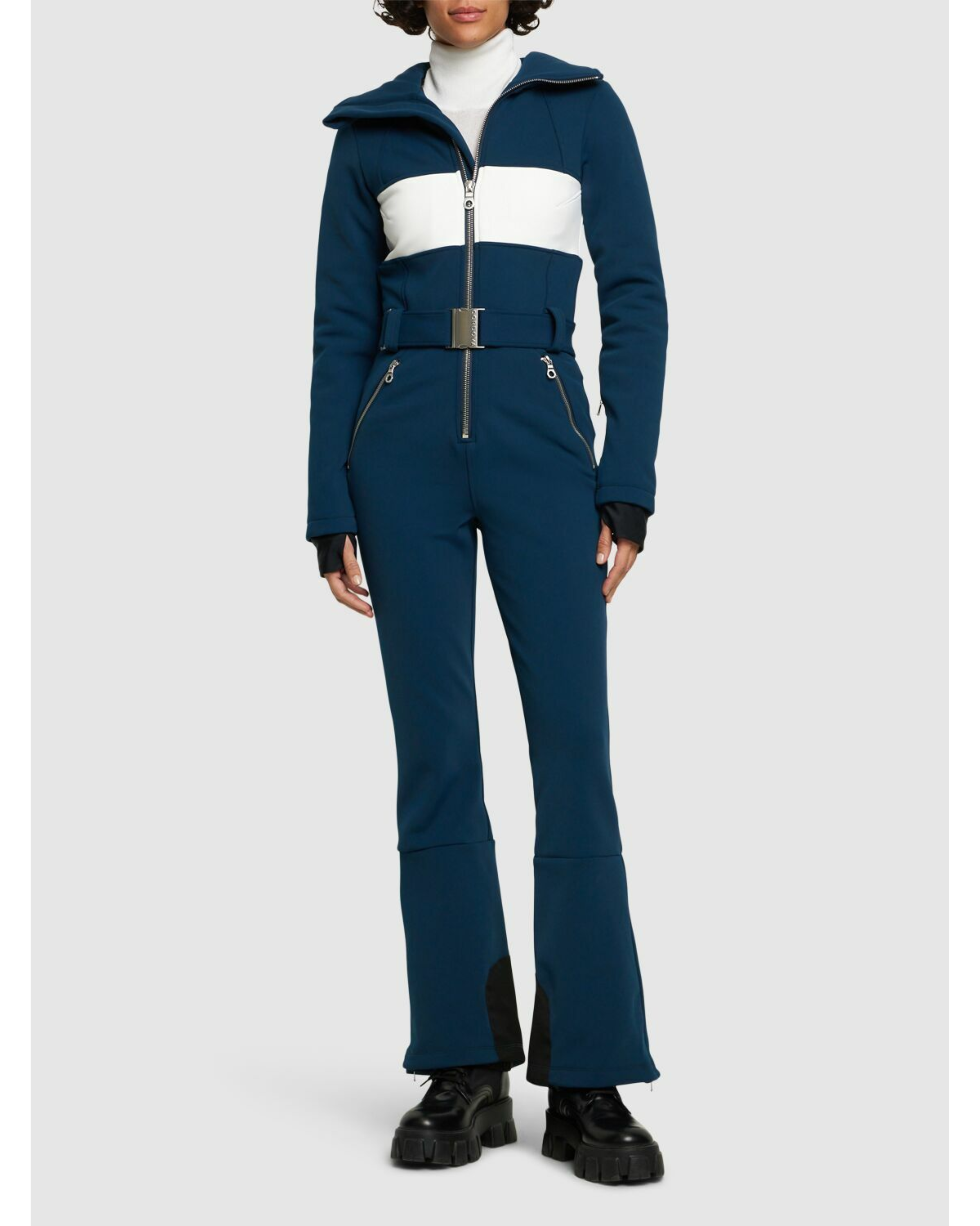 Woman wearing navy and white colorblocked ski jumpsuit with belt and black boots — Cordova | Endless UAE