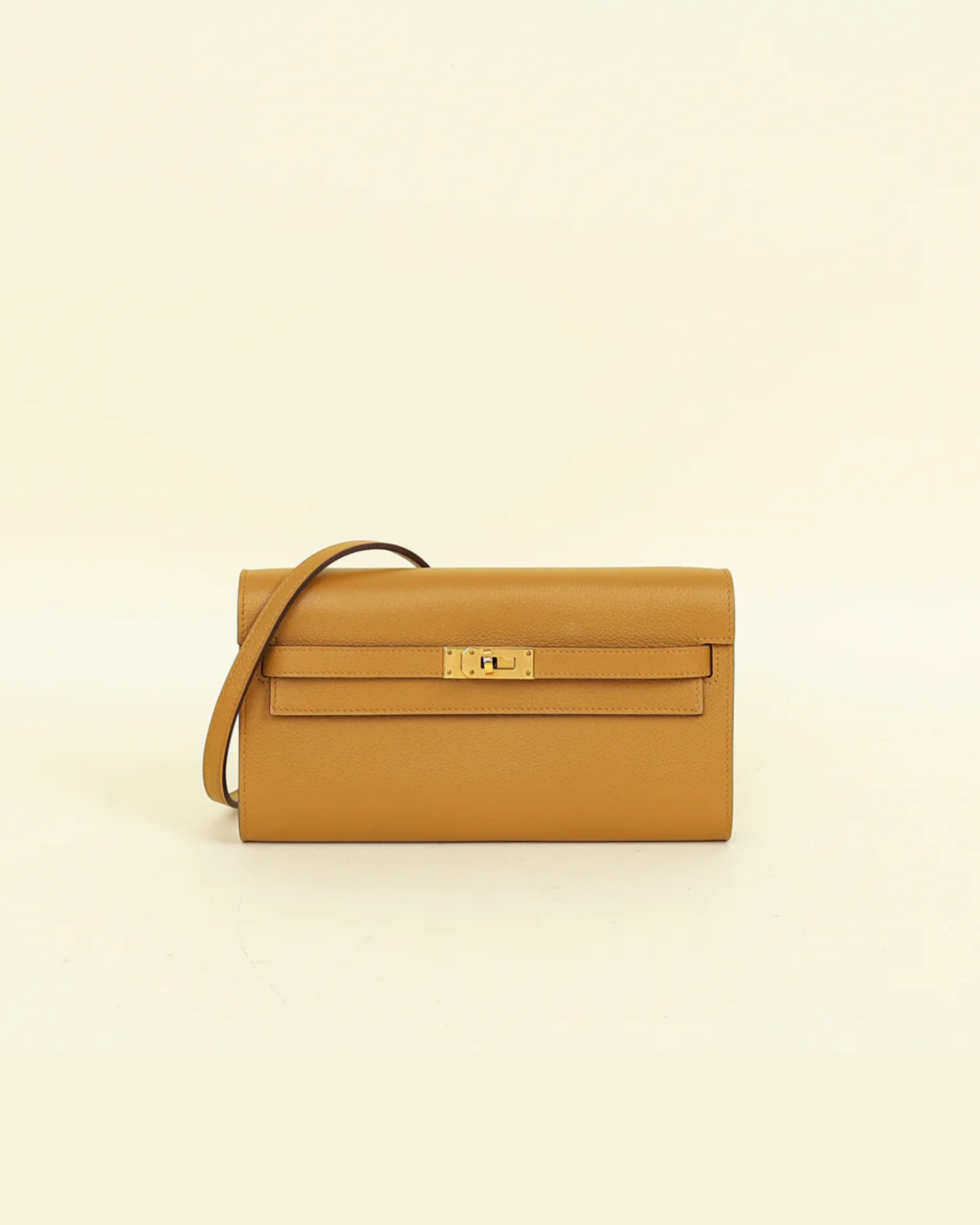 Mustard yellow leather Kelly To Go wallet with gold hardware and detachable shoulder strap on beige background — Hermes | Endless UAE