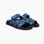 Black leather slide sandals with cutout straps displayed on orange box — Hermès | Endless UAE
