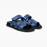 Black leather slide sandals with cutout straps displayed on orange box — Hermès | Endless UAE