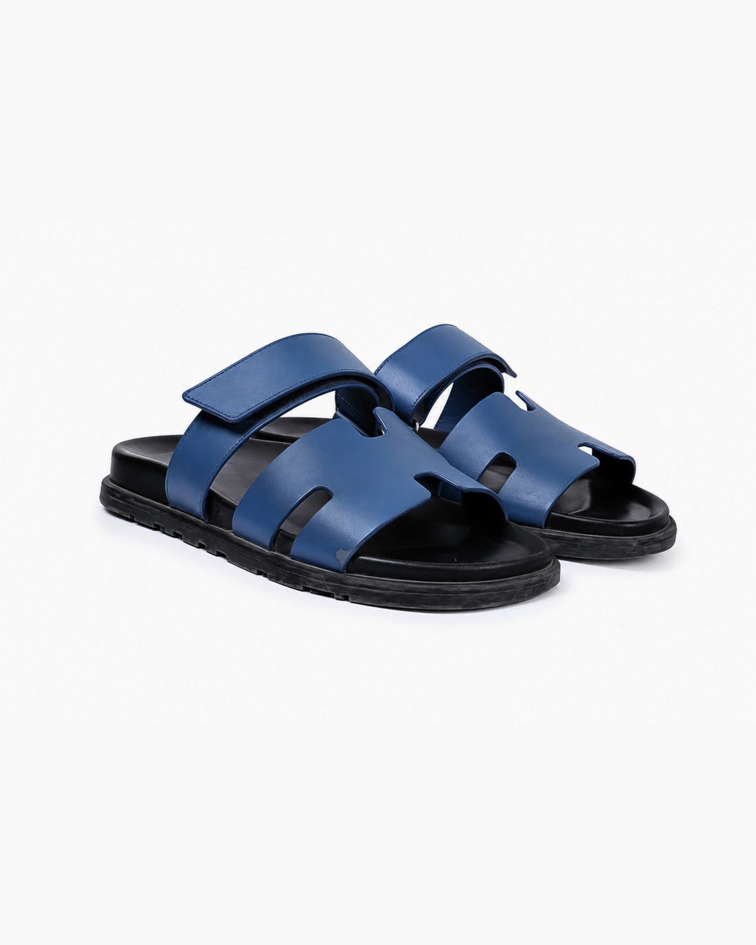 Black leather slide sandals with cutout straps displayed on orange box — Hermès | Endless UAE