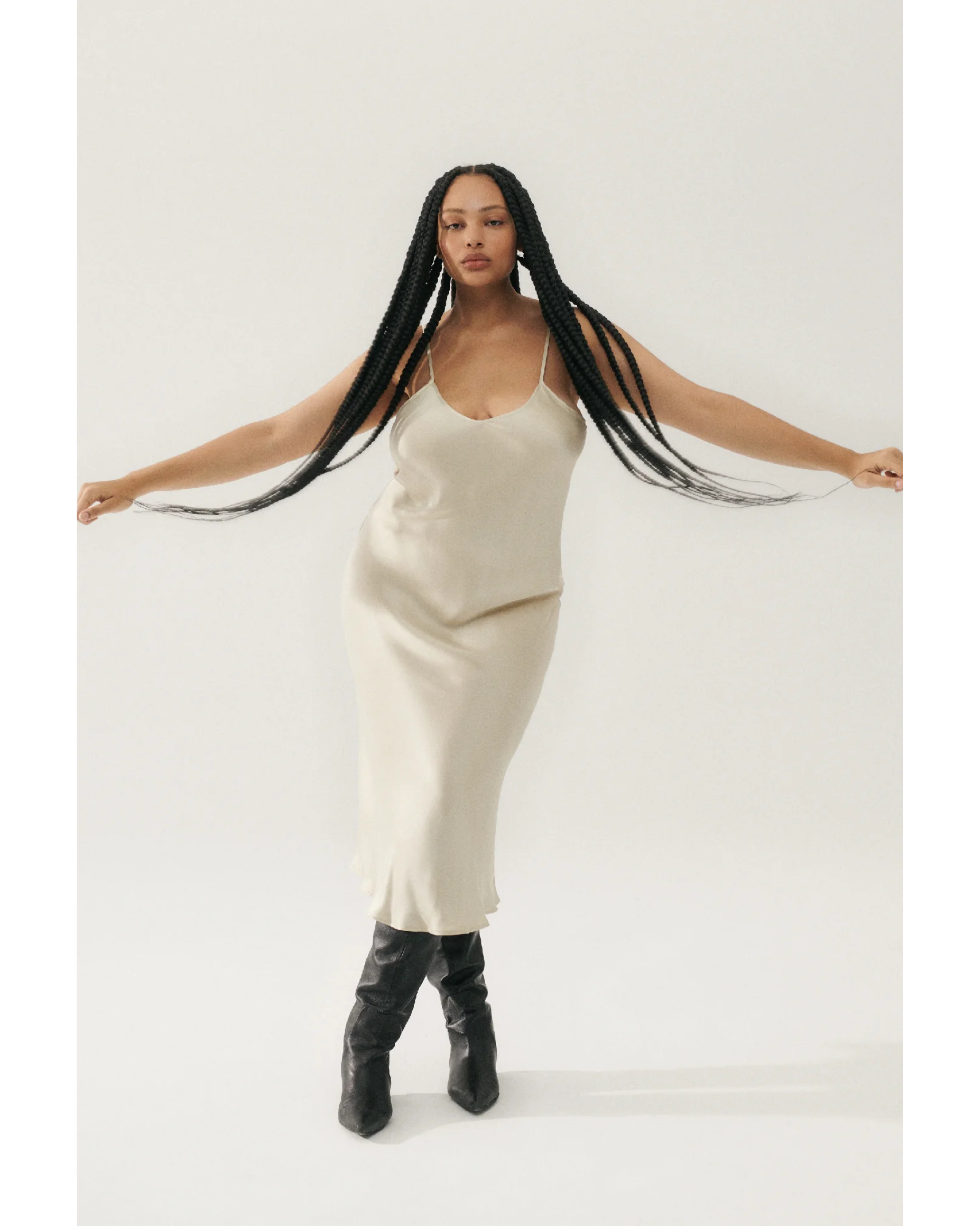 Woman wearing cream spaghetti strap slip dress with black strappy heels — Silk Laundry | Endless UAE