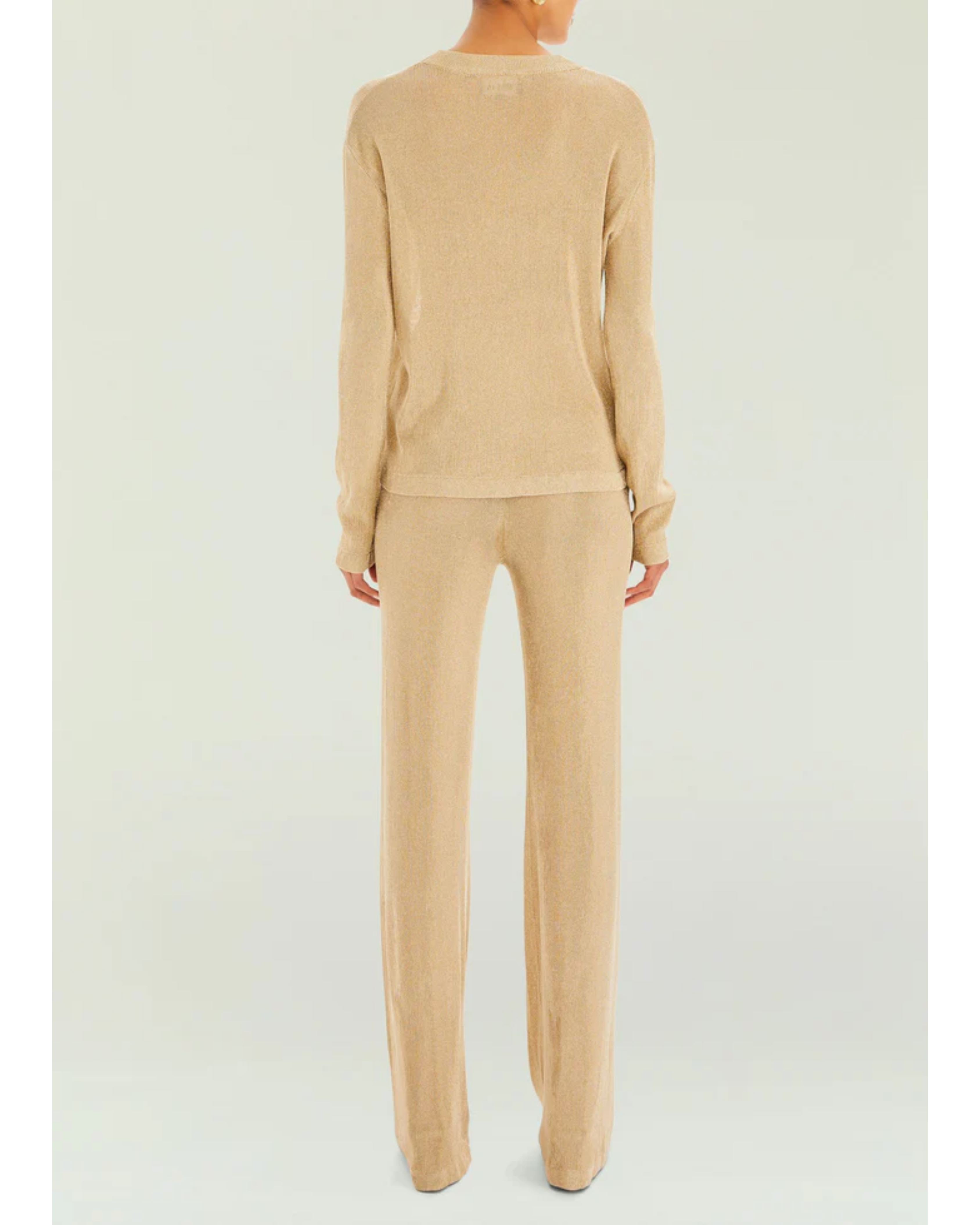 Woman wearing a beige metallic knit top and matching trousers holding a small handbag — SER.O.YA | Endless UAE