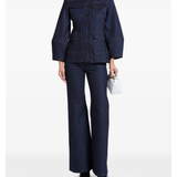 Woman wearing indigo denim jacket and flared jeans with white clutch — Florence & Fortitude | Endless UAE