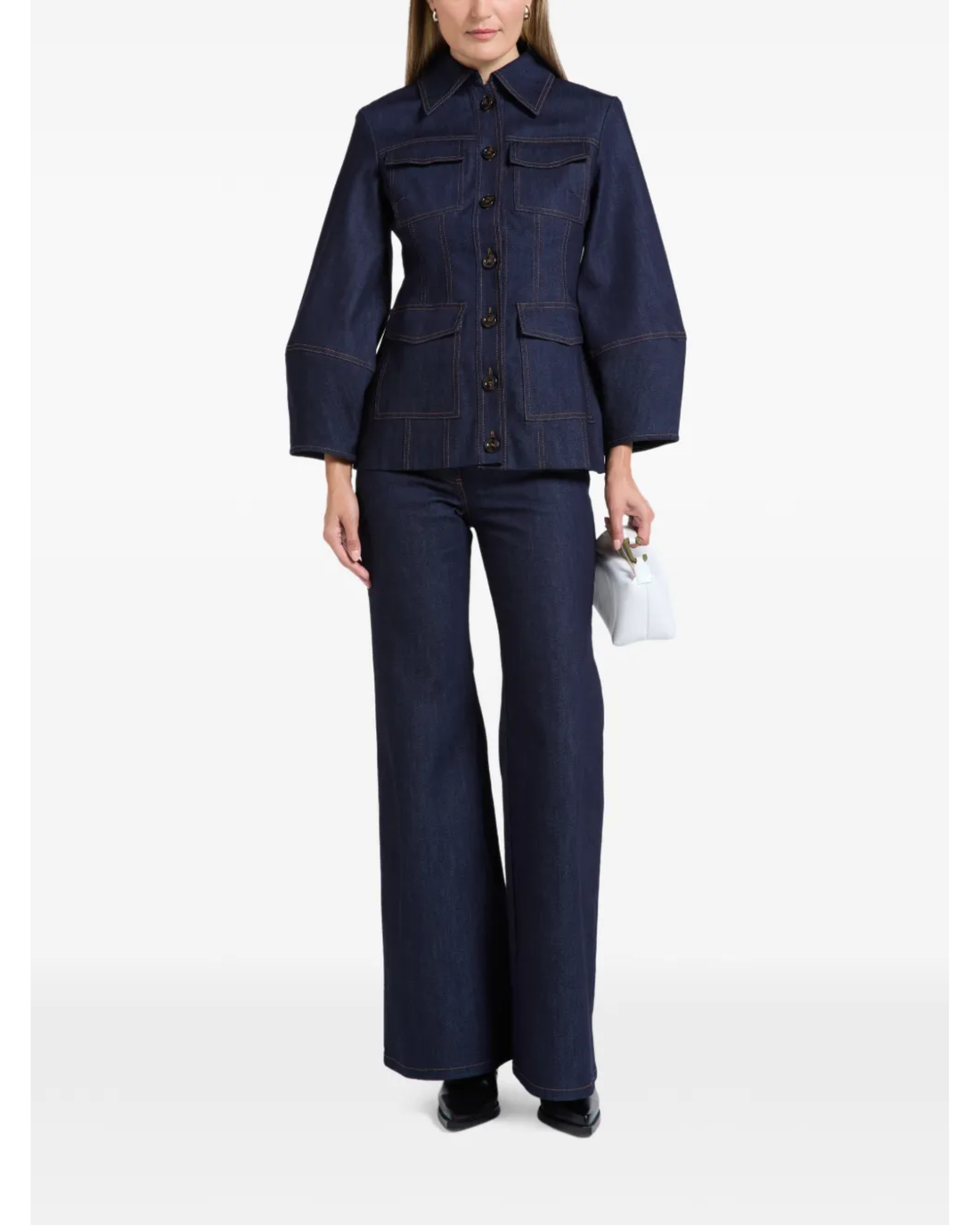 Woman wearing indigo denim jacket and flared jeans with white clutch — Florence & Fortitude | Endless UAE
