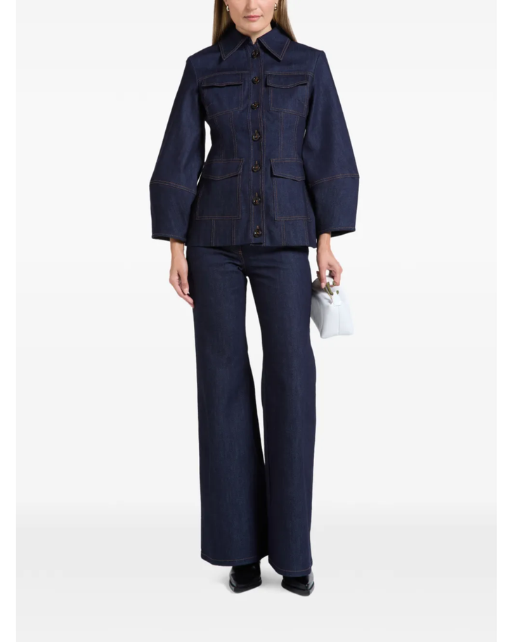 Woman wearing indigo denim jacket and flared jeans with white clutch — Florence & Fortitude | Endless UAE