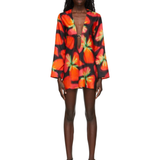 Woman wearing vibrant red and orange strawberry print blazer dress with green handbag — Louisa Ballou | Endless UAE