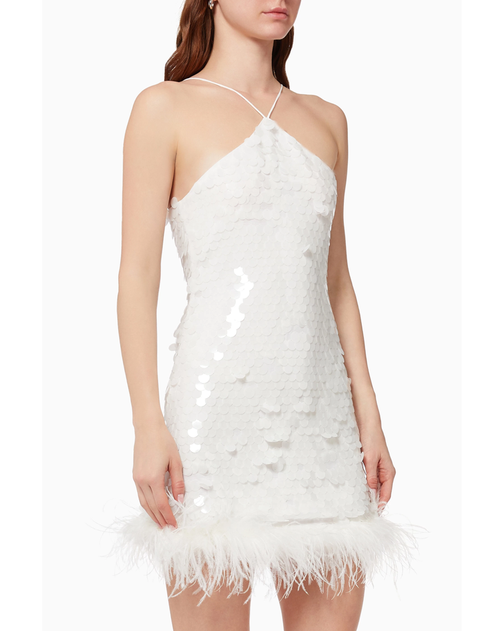 White sequin mini dress with feather hem trim and thin straps, styled with silver heels and clutch — De La Vali | Endless UAE