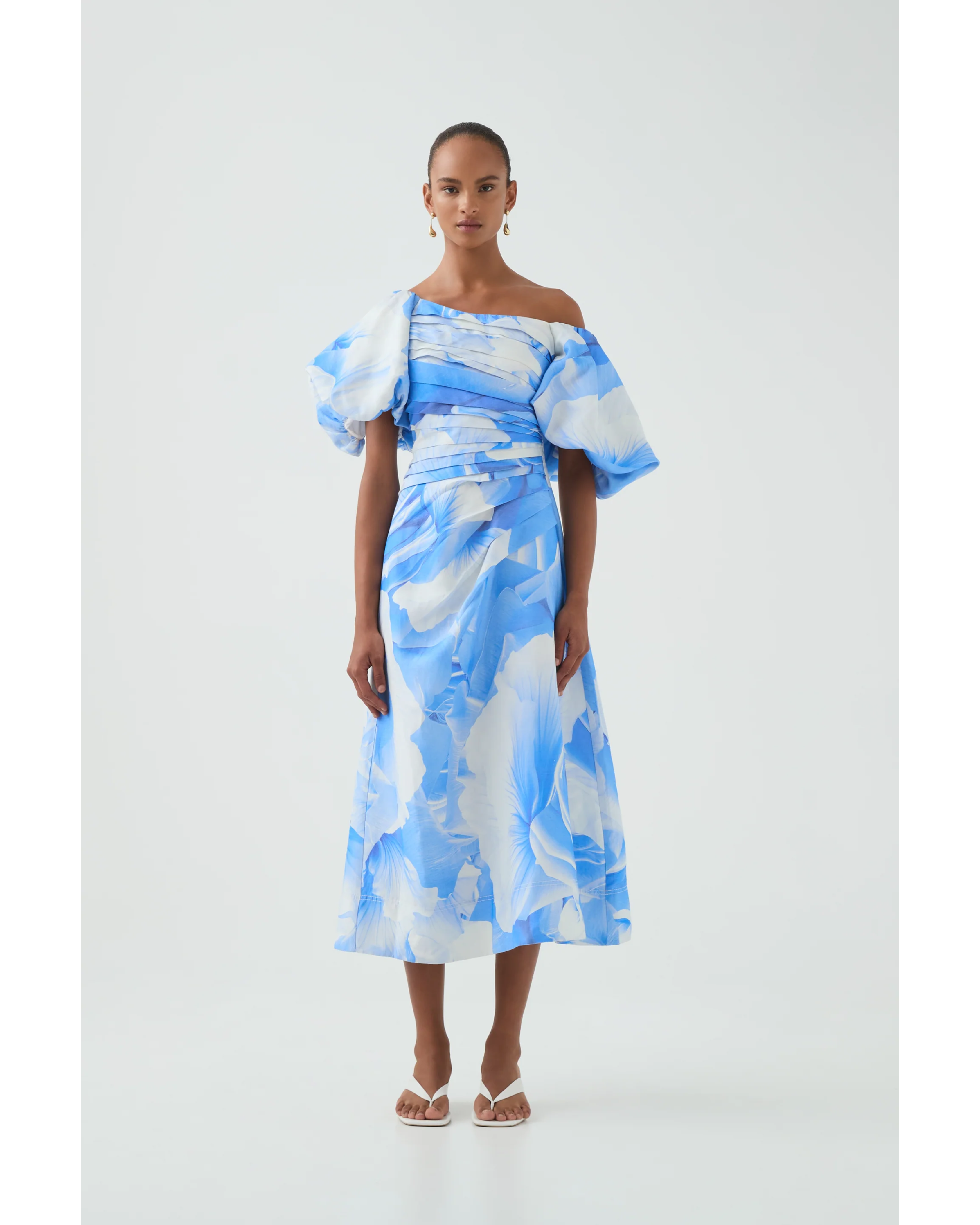 Woman wearing blue and white abstract print Cadence Ruched Midi Dress with puffed sleeves and white slides — Aje | Endless UAE