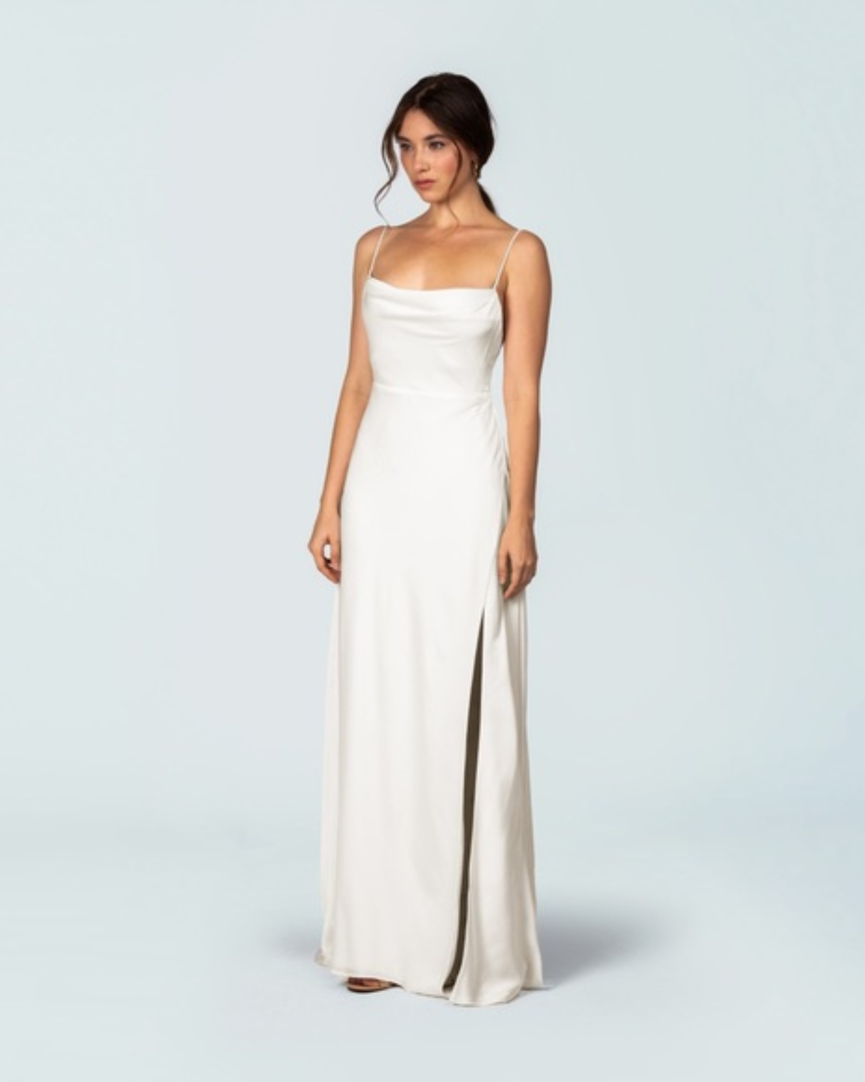 Elegant ivory satin slip gown with cowl neckline, thin straps, and high slit, full-length silhouette — Fame & Partners | Endless UAE