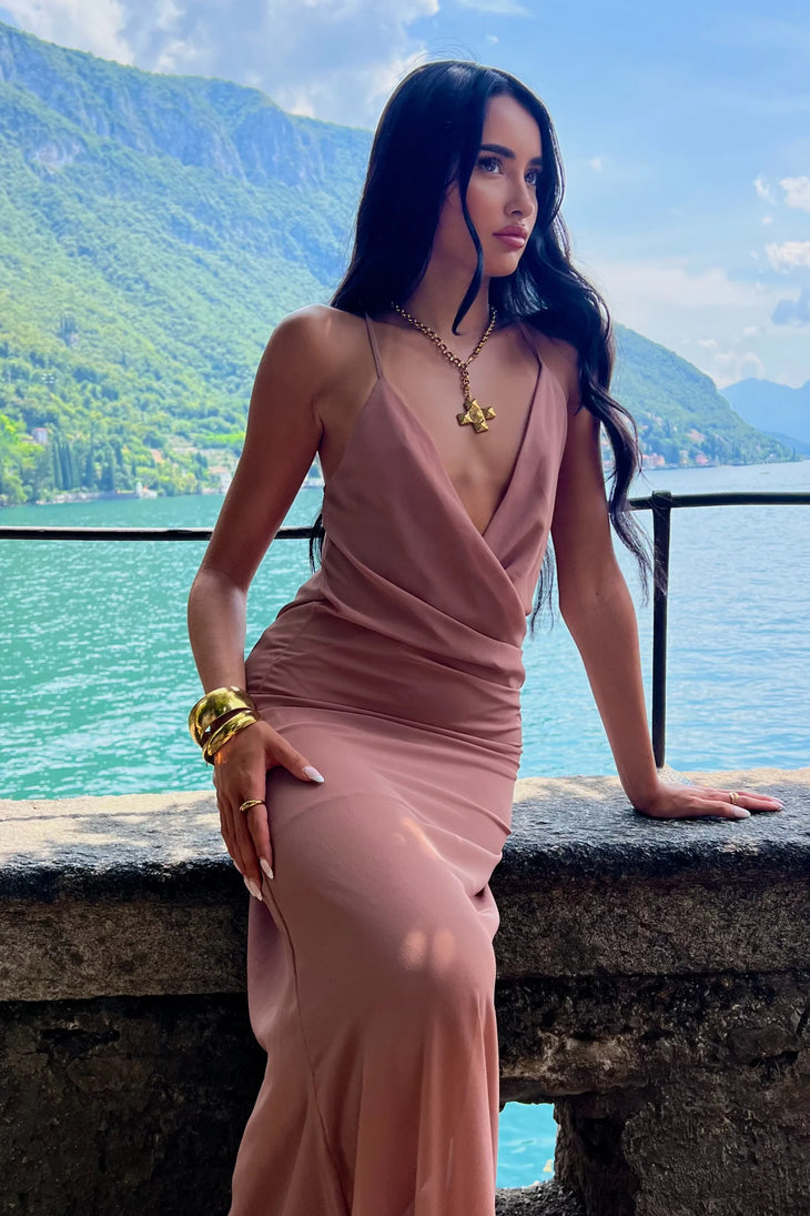 Woman wearing dusty rose Gaia Maxi Dress by a serene alpine lake with mountains — Scorpio Rizing | Endless UAE