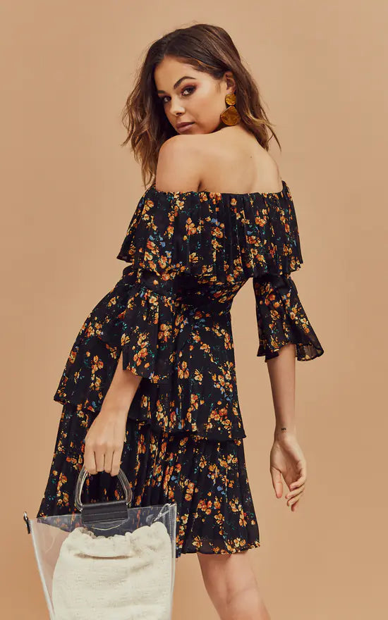 Black floral off-shoulder mini dress with tiered ruffles and bell sleeves, model holding clear handbag — Bardot | Endless UAE