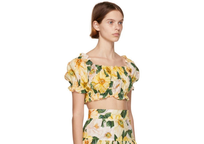 Model wearing yellow floral print crop top and matching skirt set with green leaves on beige background — Dolce and Gabbana | Endless UAE
