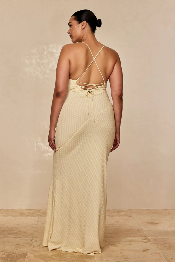 Rear view of woman wearing a cream satin maxi dress with criss-cross back straps and tie detail — Monday Swimwear | Endless UAE