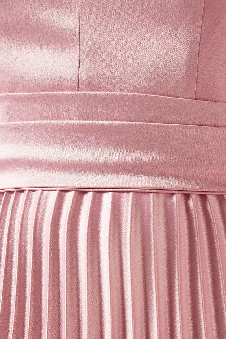 Woman wearing a pink satin pleated dress with matching cape overlay and metallic heels — Nass | Endless UAE