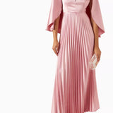 Woman wearing a pink satin pleated dress with matching cape overlay and metallic heels — Nass | Endless UAE