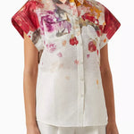 Woman wearing floral print blouse and wide-leg pants with brown handbag — Leo Lin | Endless UAE